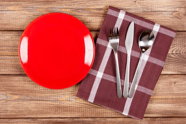 Red plate on a wooden table — Stock Photo, Image
