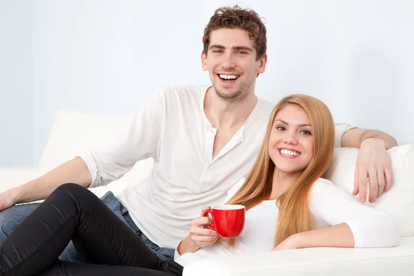 Jeune beau couple sur un canapé à la maison — Photo