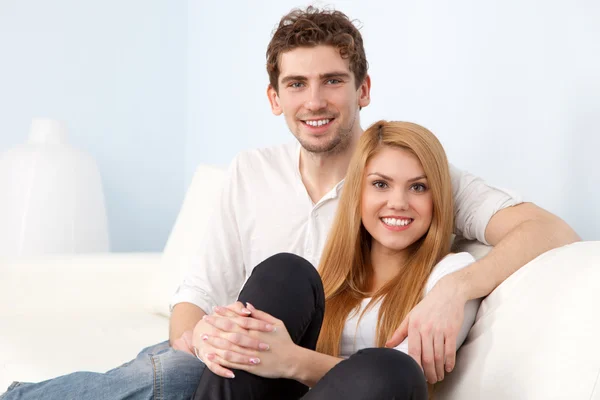 Jovem casal bonito em um sofá em casa — Fotografia de Stock