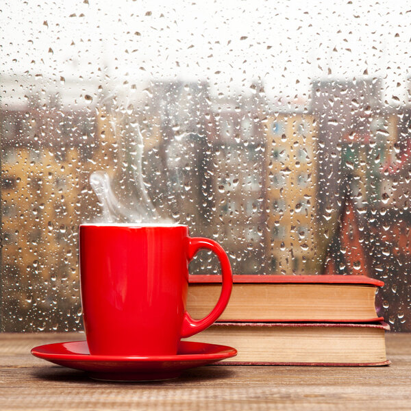 Steaming coffee cup on a rainy day window background