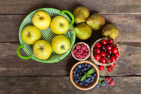 Čerstvá šťavnatá jablka, hrušky a bobule na dřevěný stůl — Stock fotografie