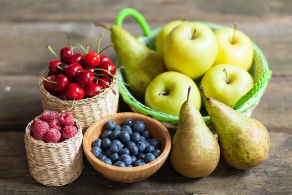 Fresh juicy apples, pears and berries on a wooden table