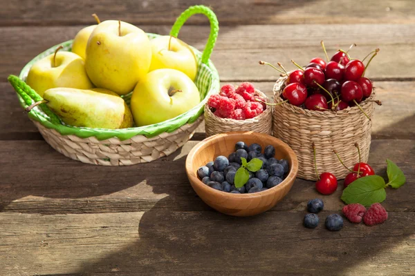 Свежие сочные яблоки, груши и ягоды на деревянном столе — стоковое фото