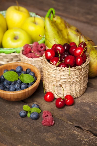 Свежие сочные яблоки, груши и ягоды на деревянном столе — стоковое фото
