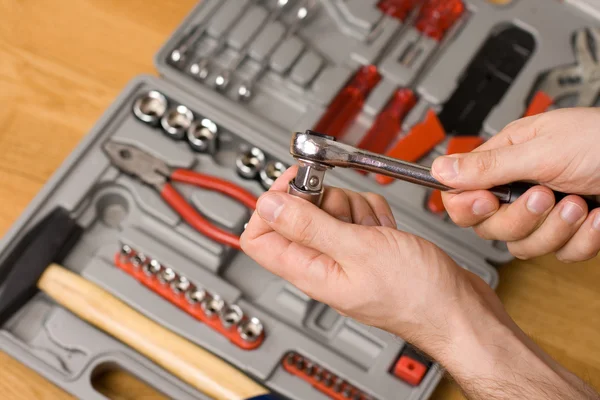Hands holding ratchet and head over toolbox — Stock Photo, Image