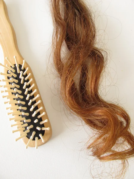 Hakiki Kumral saç strand ve bir saç fırçası — Stok fotoğraf
