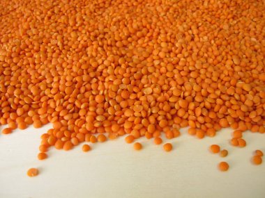 Kırmızı mercimekler tahta bir tahtaya saçılmış.