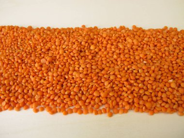 Kırmızı mercimekler tahta bir tahtaya saçılmış.