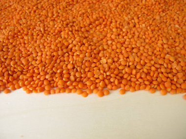 Kırmızı mercimekler tahta bir tahtaya saçılmış.