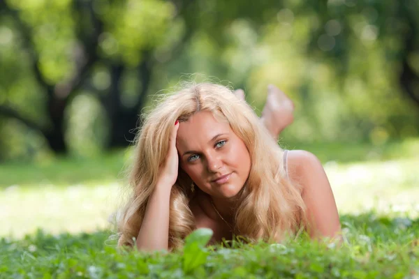 Блондинка лежит на траве — стоковое фото