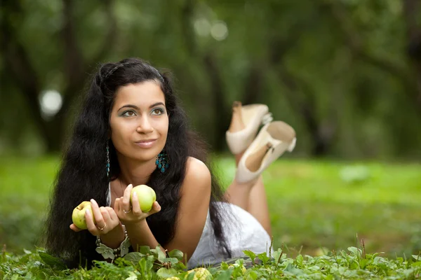 A menina em uma grama e maçãs — Fotografia de Stock
