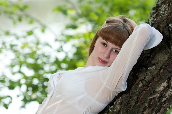 De vrouw leunde de ellebogen op een boom — Stockfoto