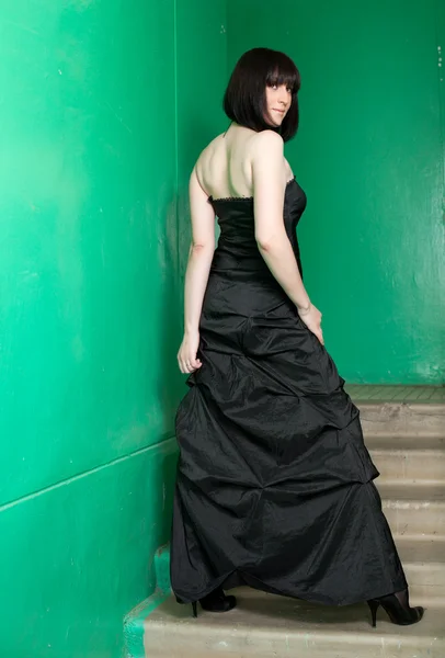 La donna in un vestito nero costa su una scala — Foto Stock