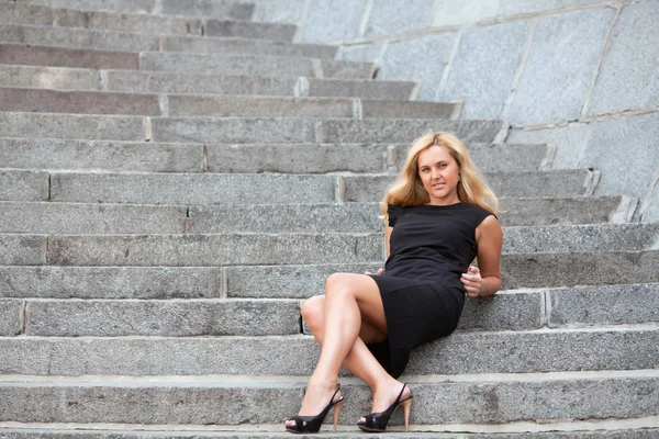 A bela mulher senta-se em uma escada — Fotografia de Stock