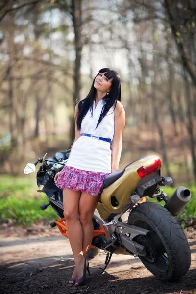 Uma menina está ao lado de uma motocicleta — Fotografia de Stock