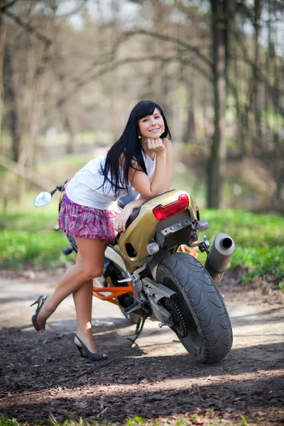 Una chica está de pie junto a una motocicleta —  Fotos de Stock