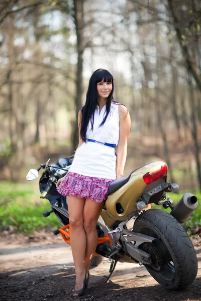 Uma menina está ao lado de uma motocicleta — Fotografia de Stock