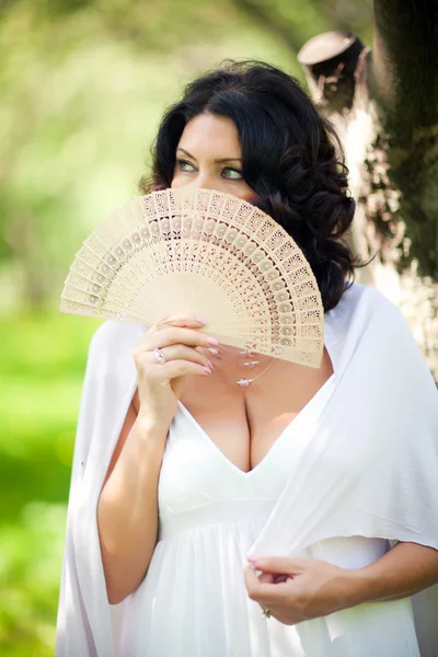 A woman in the park holds a fan — Stock Photo, Image