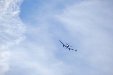 Mavi gökyüzü ve bulutların arka planında uçan uçak