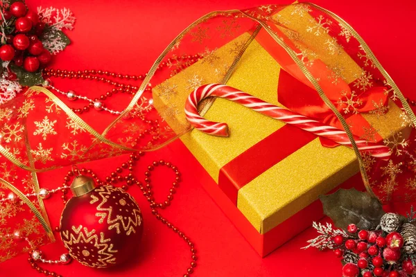 赤い背景にギフトとクリスマスの装飾が施された箱の上のロリポップ杖 — ストック写真