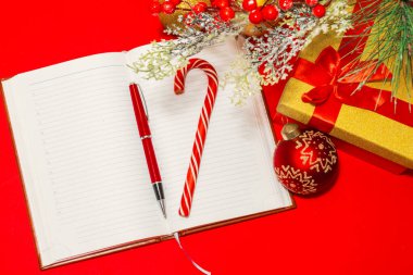 Güzel kalem ve lolipop bastonu kırmızı masa ve Noel süslemeleri üzerinde not defterinde