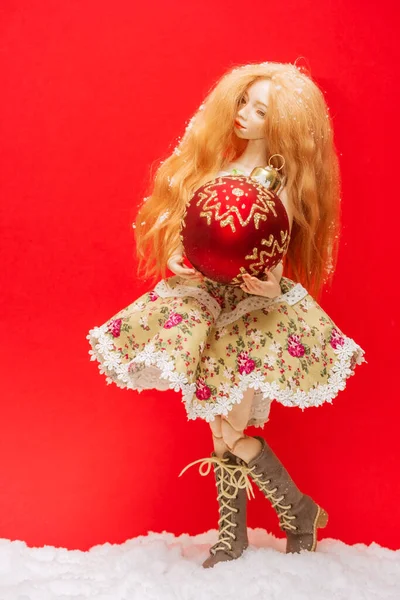 Piękna Dziewczyna Lalka Piłką Świąteczną Rękach Czerwonym Tle — Zdjęcie stockowe