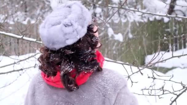 毛皮のコートと帽子を着た大人の女性は 赤いスカーフで向きを変え 雪の中で喜び スローモーションでキスをします — ストック動画