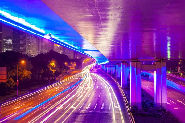 Pohybující se auto s rozmazaným světlem přes město v noci — Stock fotografie