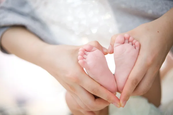 La mano de la madre sostiene el pie del bebé — Foto de Stock