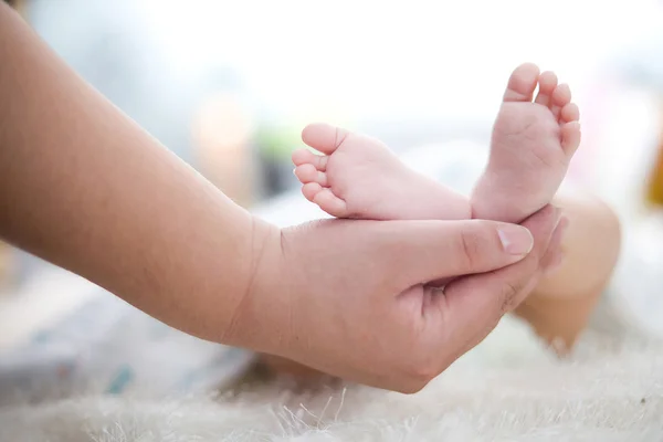 La mano de la madre sostiene el pie del bebé — Foto de Stock