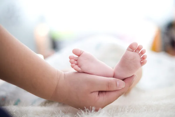 La mano della mamma tiene il piede del bambino — Foto Stock