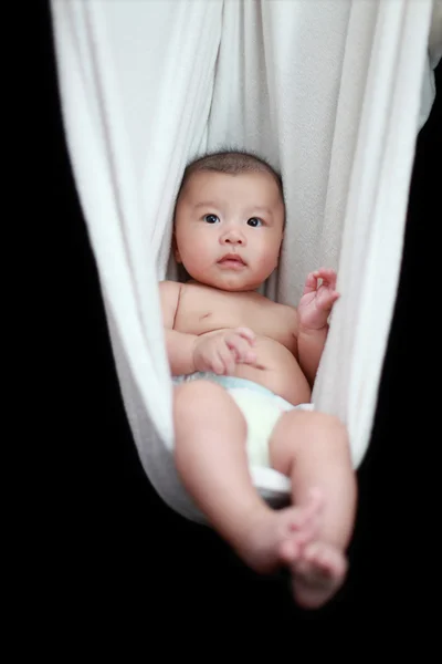 Bebé desnudo durmiendo en el cabestrillo blanco de la hamaca, aislado en un fondo negro . — Foto de Stock