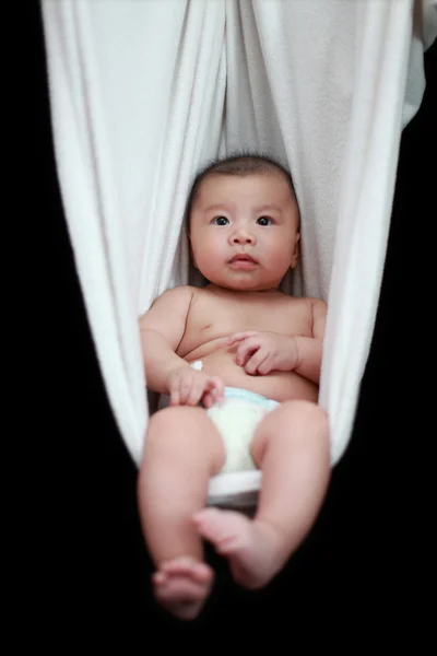Bebé desnudo durmiendo en el cabestrillo blanco de la hamaca, aislado en un fondo negro . — Foto de Stock