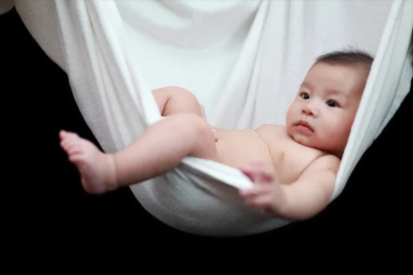 Γυμνός μωρό που κοιμάται σε άσπρη αιώρα σφεντόνα, απομονωμένη σε ένα μαύρο φόντο. — Φωτογραφία Αρχείου