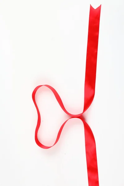 Shiny red satin ribbon with heart shape on white background with copy space. Macro with extremely shallow dof. — Stock Photo, Image