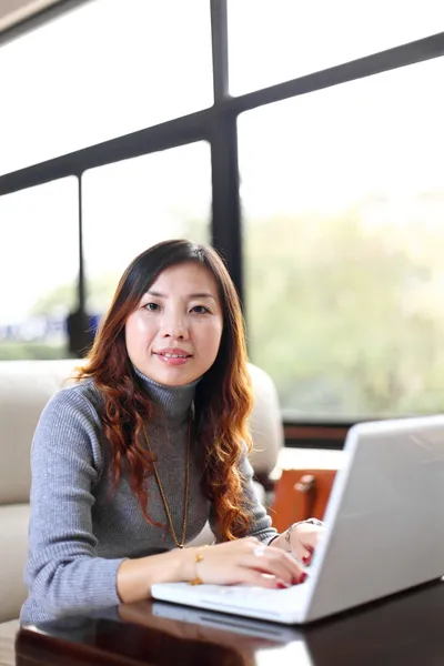 Lachende Aziatische zakelijke vrouw met laptop — Stockfoto