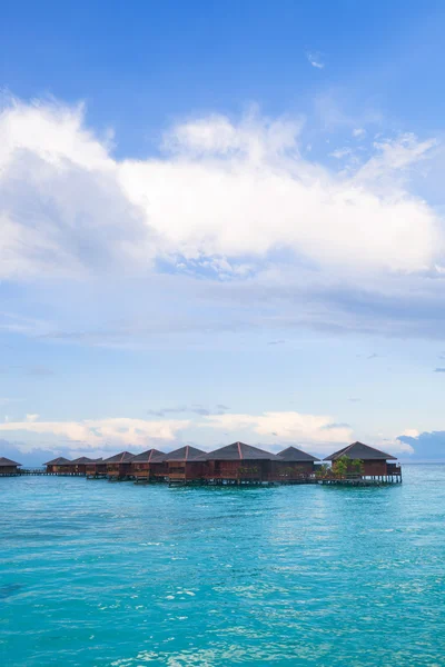 Bungalow sobre agua con cielo bullicioso — Foto de Stock