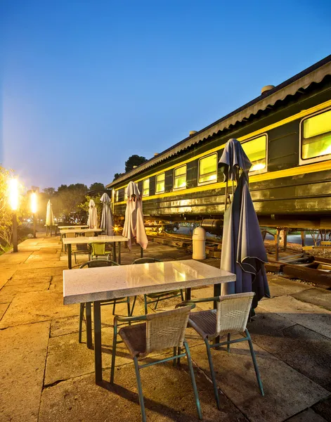 Outdoor cafe bar with an old train background — Stock Photo, Image