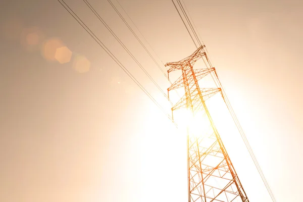 Високовольтні вежі передачі електроенергії на фоні неба заходу сонця — стокове фото