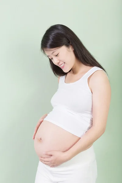 漂亮的孕妇肚子还盯着她的手的照片 — 图库照片