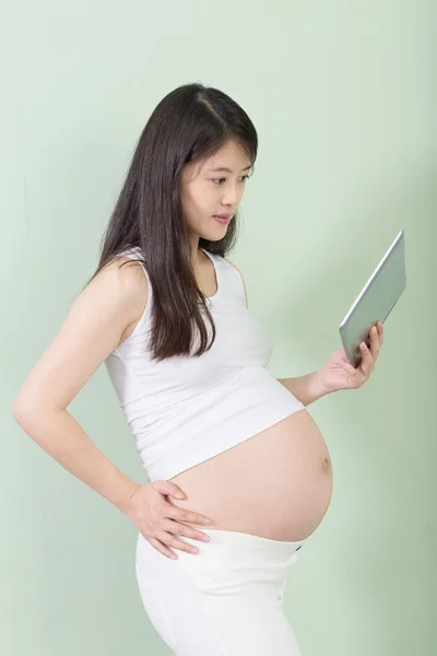 Hermosa mujer embarazada con almohadilla en la mano —  Fotos de Stock