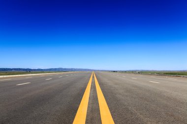 Highway in steppe against a blue sky clipart