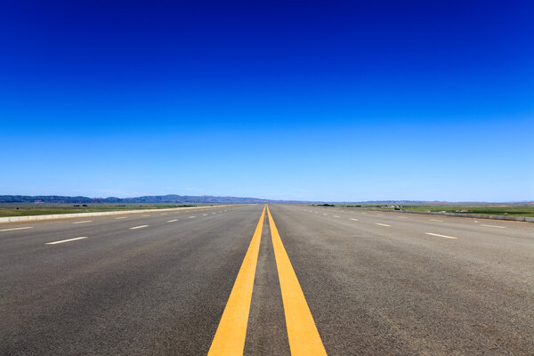 Highway in steppe against a blue sky
