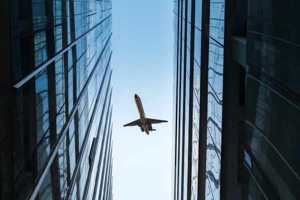 Arranha-céus de vidro e avião — Fotografia de Stock