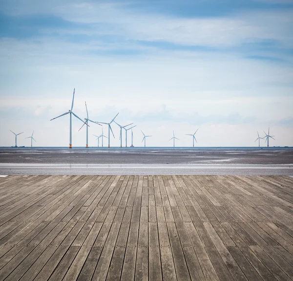 Wind farm in mud flat with wooden floor — Stock Photo, Image