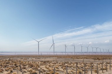 Sonbaharda çöl arazisindeki rüzgâr tarlası, mavi gökyüzüne karşı temiz enerji manzarası.