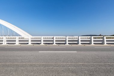 Asfalt yol yüzeyi modern köprüyle mavi gökyüzüne karşı