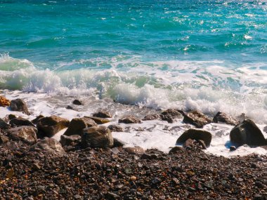 Şeffaf deniz dalgaları ve dinlenmek için kayalık bir plaj.