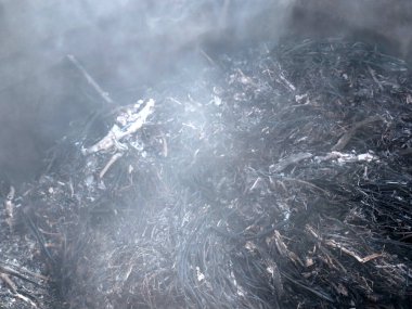 Yerel alanı temizlerken gri duman ve yanmış çimen sapları