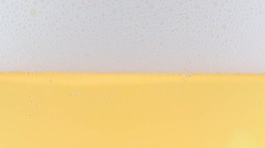 Yüzeydeki köpükte bir bardak hafif bira ve hava kabarcıkları.